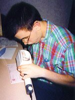 A young man using a special magnifying device to read a check.